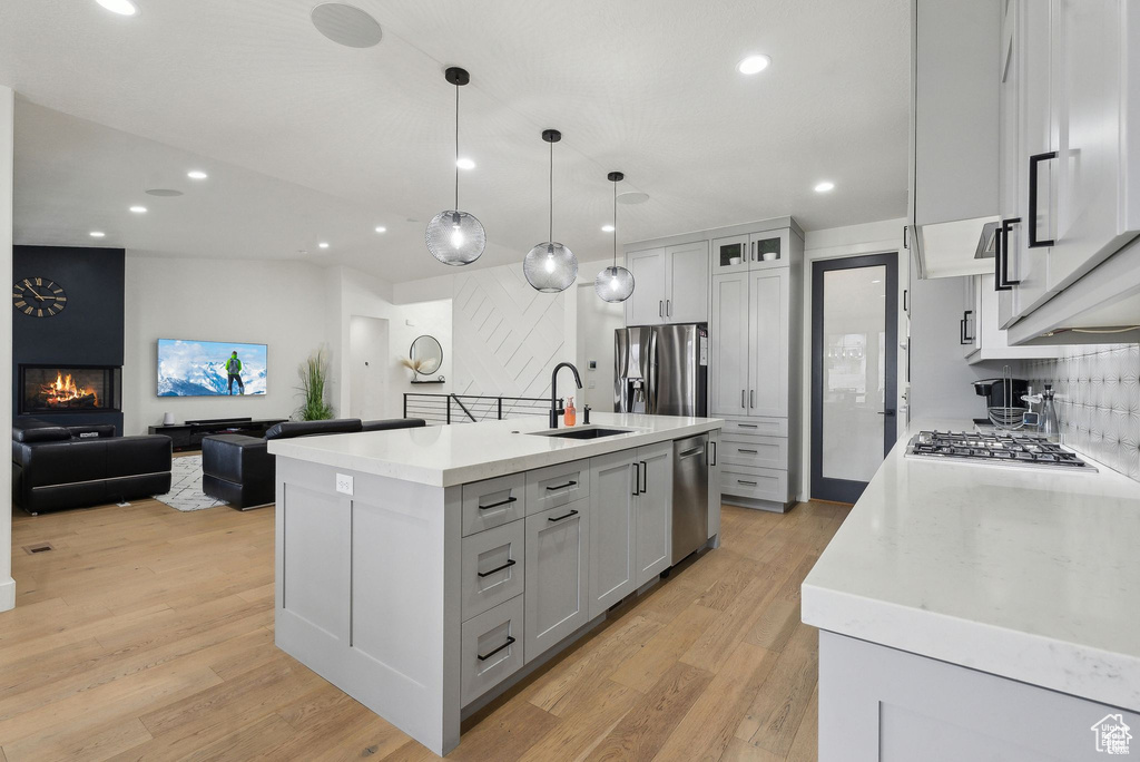 Kitchen with appliances with stainless steel finishes, recessed lighting, light wood-style flooring, a sink, and a kitchen island with sink