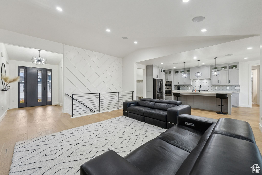 Living room featuring light wood-style flooring, vaulted ceiling, baseboards, and recessed lighting
