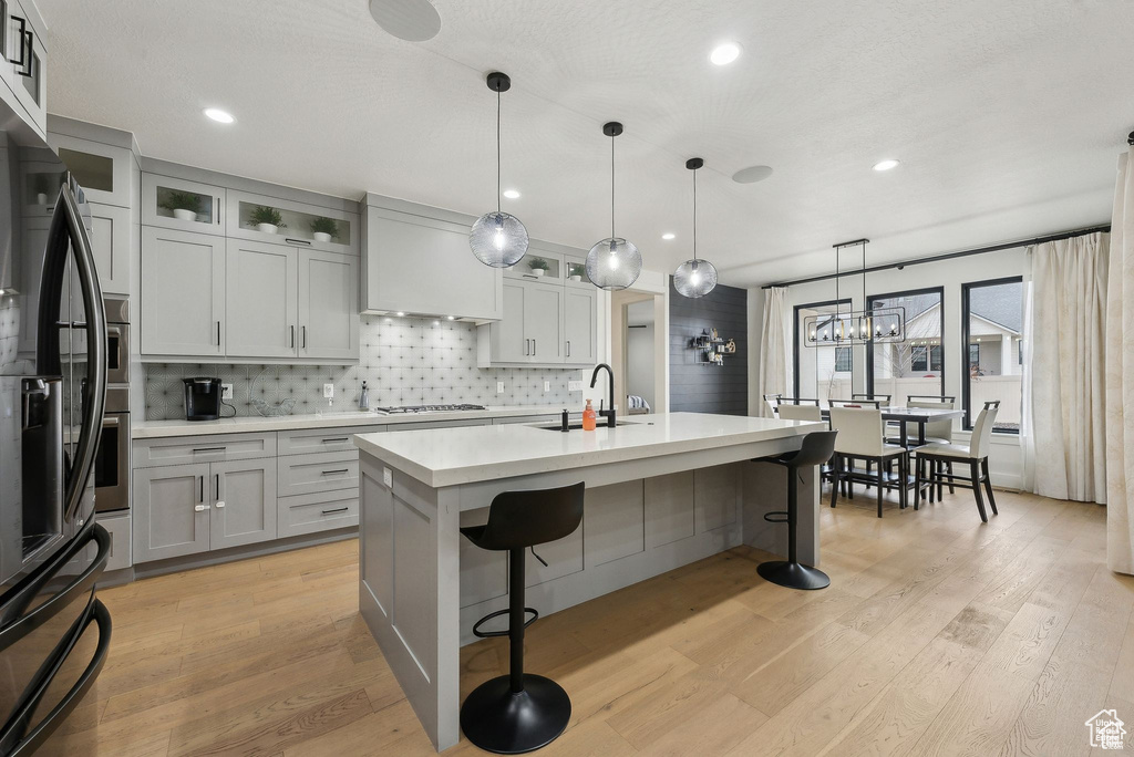 Kitchen featuring light countertops, gas cooktop, a breakfast bar area, light wood finished floors, and backsplash