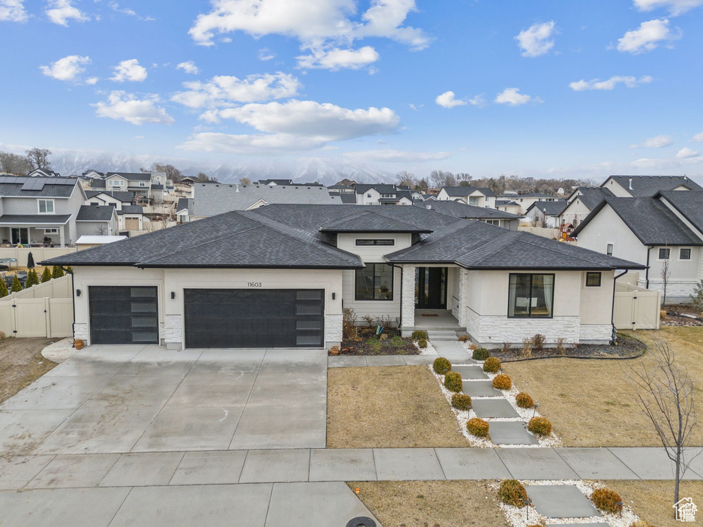 View of front of home with roof with shingles, a residential view, an attached garage, and stone siding