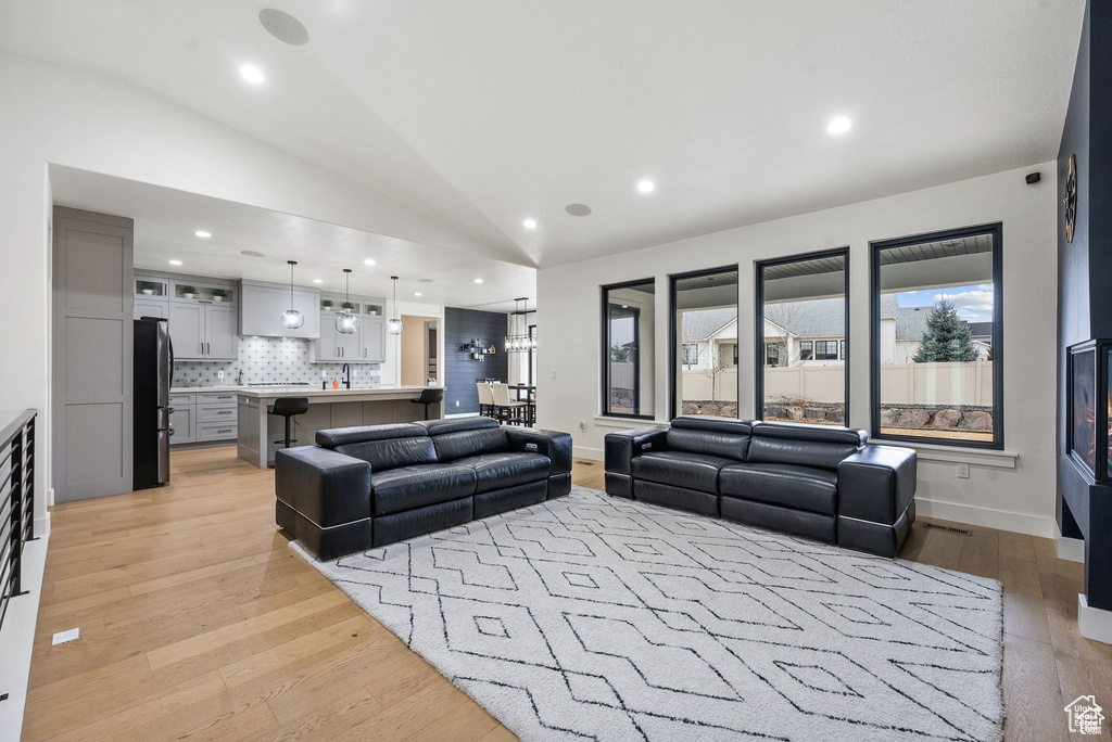 Living area featuring lofted ceiling, light wood finished floors, recessed lighting, and baseboards