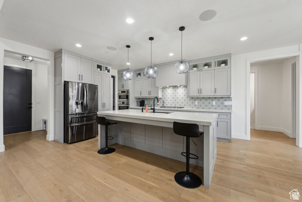 Kitchen with stainless steel appliances, light countertops, backsplash, a kitchen bar, and recessed lighting