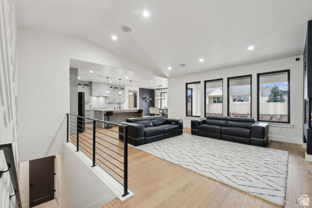 Living area featuring light wood-style flooring, lofted ceiling, and recessed lighting