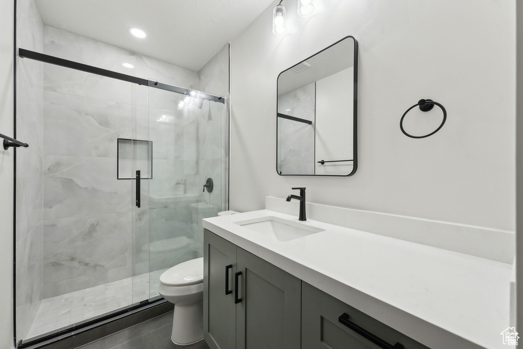 Full bathroom with toilet, vanity, and a stall shower