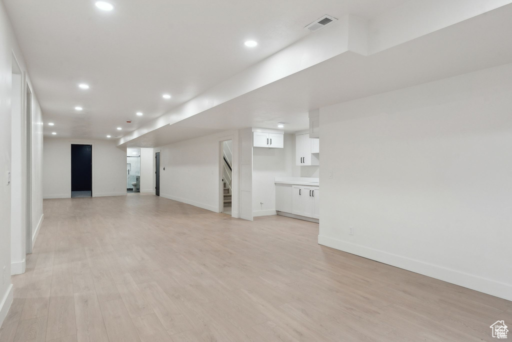 Unfurnished living room featuring baseboards, recessed lighting, stairs, and light wood-style flooring