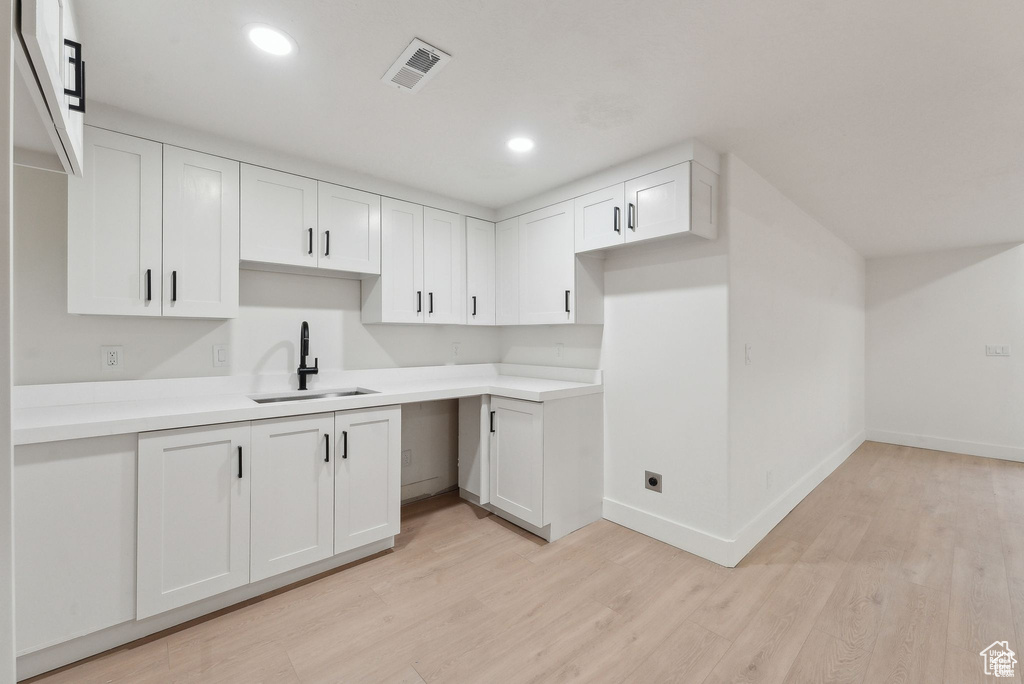 Kitchen with a sink, baseboards, light wood-style floors, white cabinets, and recessed lighting