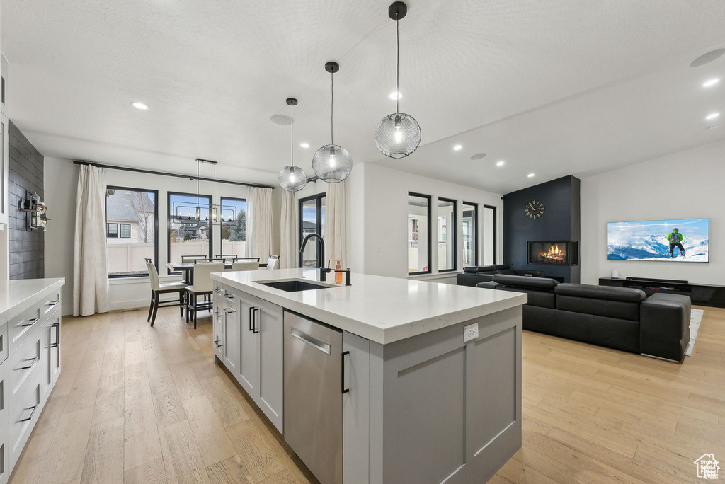 Kitchen featuring a sink, light wood-type flooring, recessed lighting, a kitchen island with sink, and dishwasher