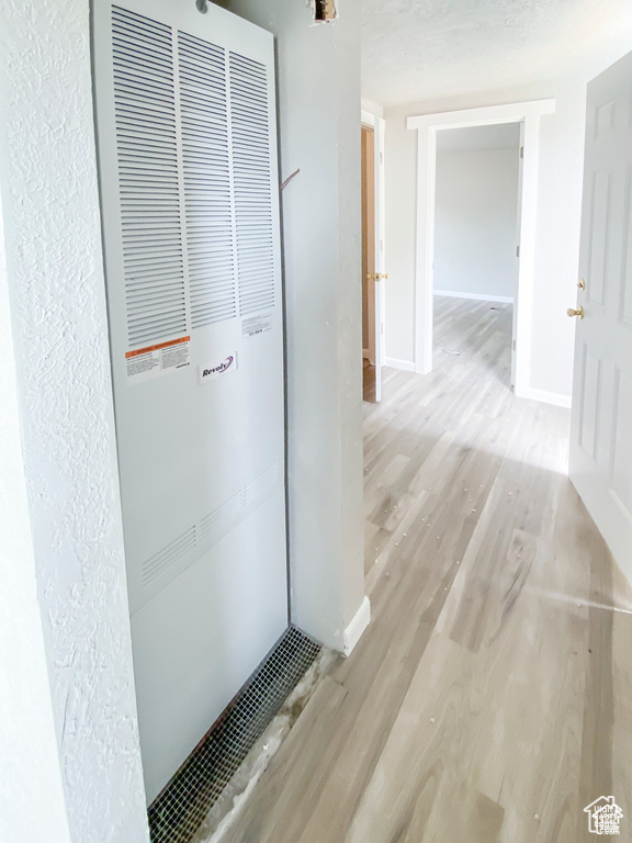 Hallway featuring a heating unit, wood finished floors, and baseboards