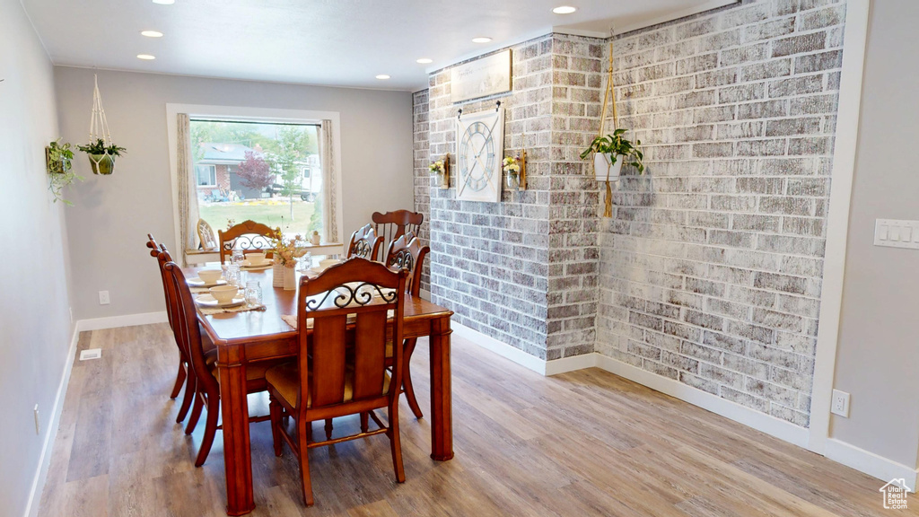 Dining area featuring baseboards, wood finished floors, recessed lighting, and brick wall