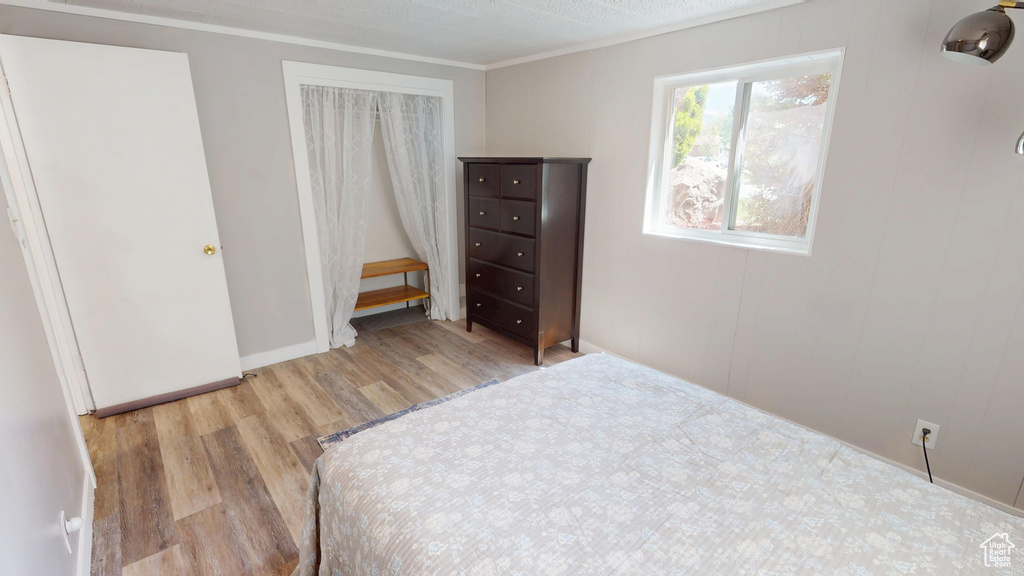 Bedroom with wood finished floors, crown molding, a closet, and baseboards