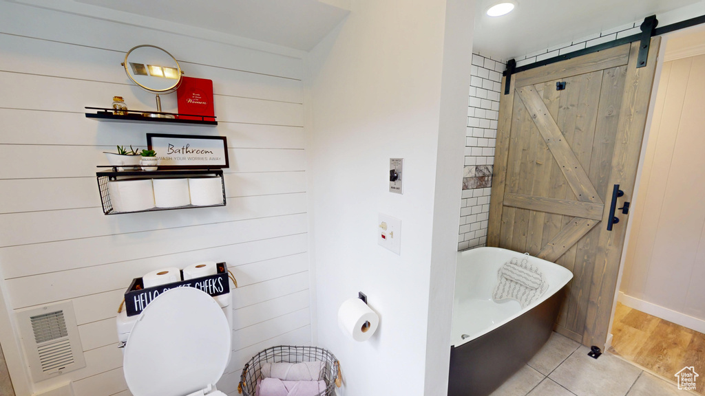 Bathroom featuring a soaking tub, wood walls, and toilet