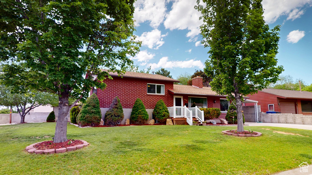 View of front of house featuring a chimney, driveway, an attached garage, and brick siding