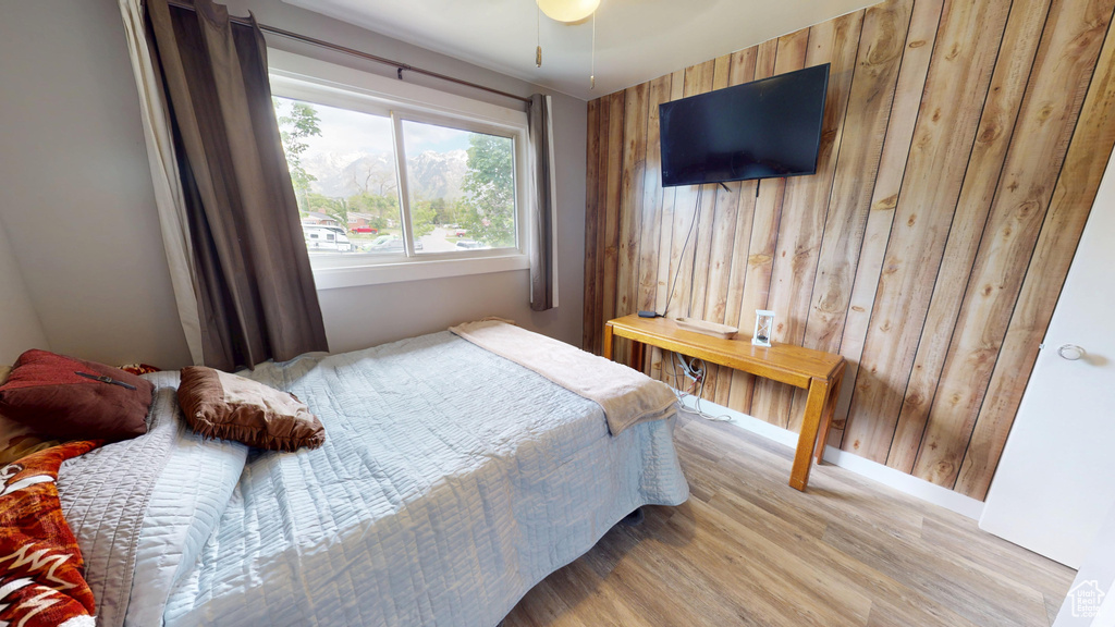 Bedroom with wood finished floors, wood walls, and baseboards