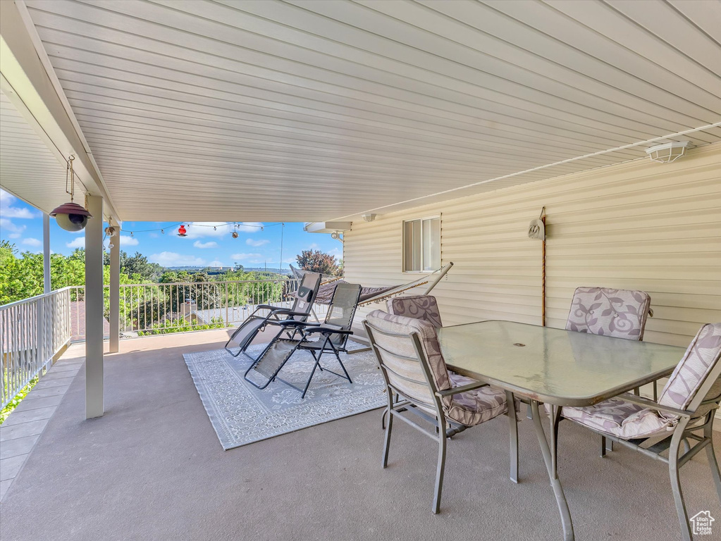 View of patio with outdoor dining area and a balcony