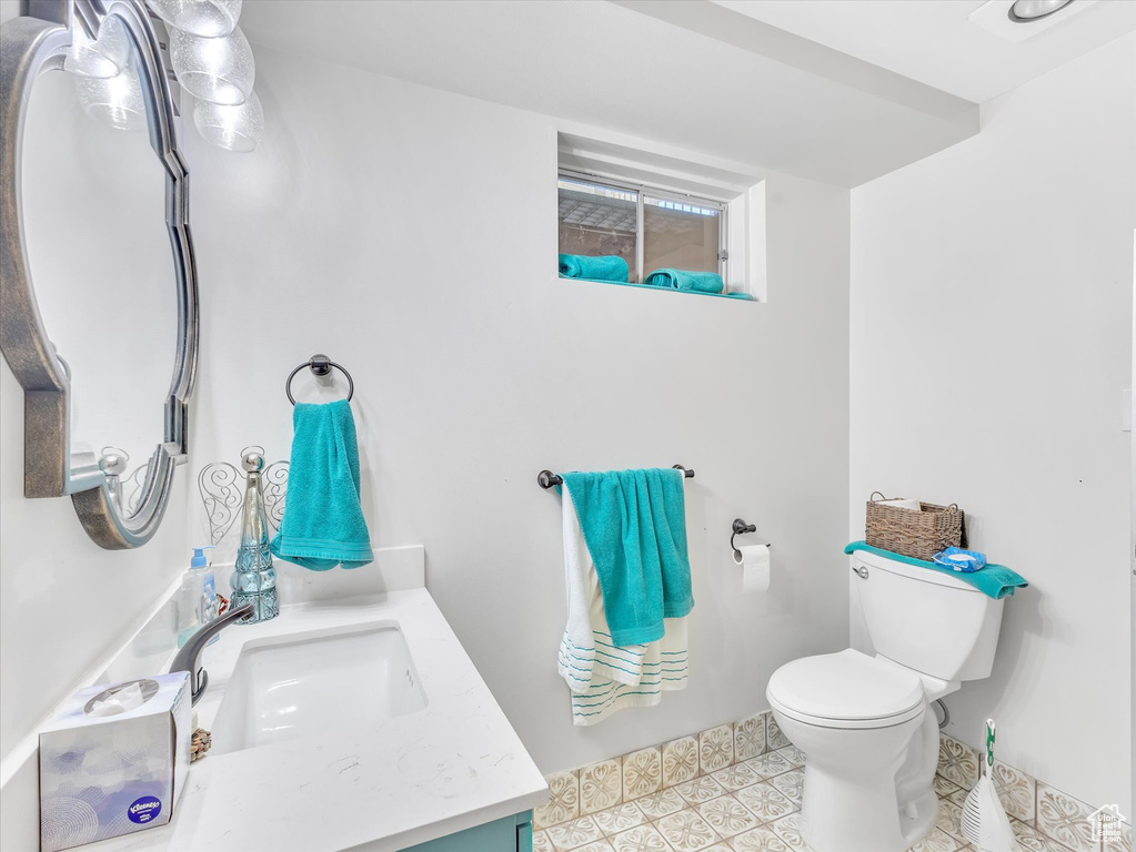Half bath featuring vanity, toilet, and tile patterned flooring