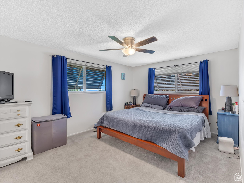 Bedroom with light colored carpet, a ceiling fan, baseboards, a textured ceiling, and refrigerator
