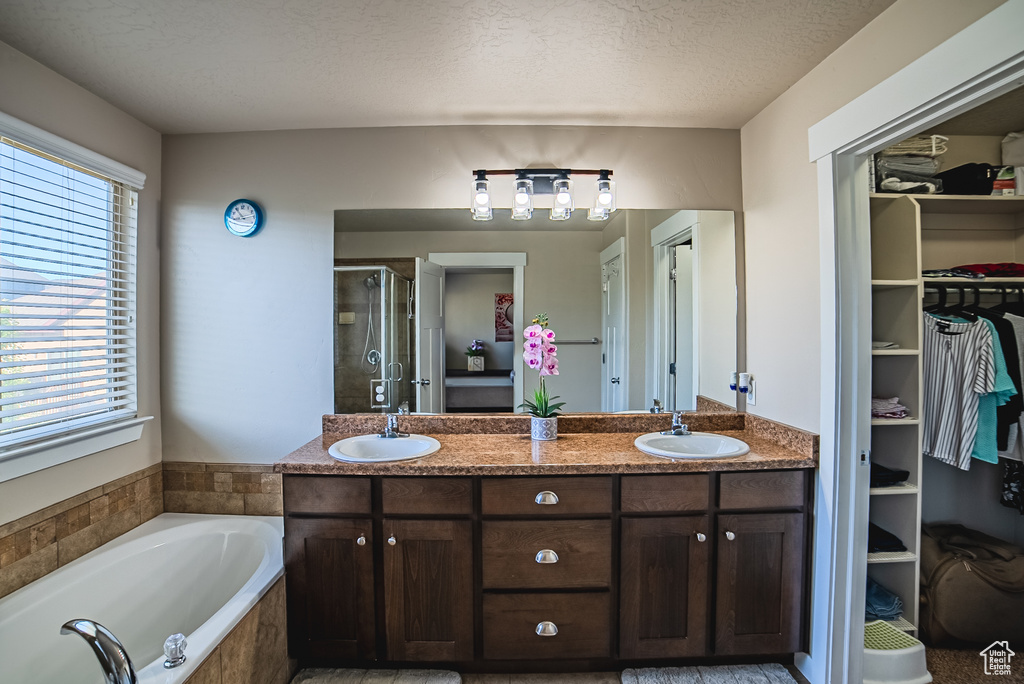 Full bath featuring healthy amount of natural light, a shower stall, a bath, a walk in closet, and a textured ceiling
