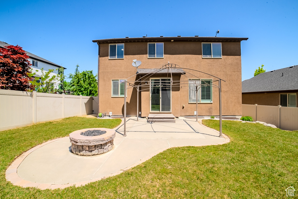 Back of property featuring stucco siding, an outdoor fire pit, and a patio