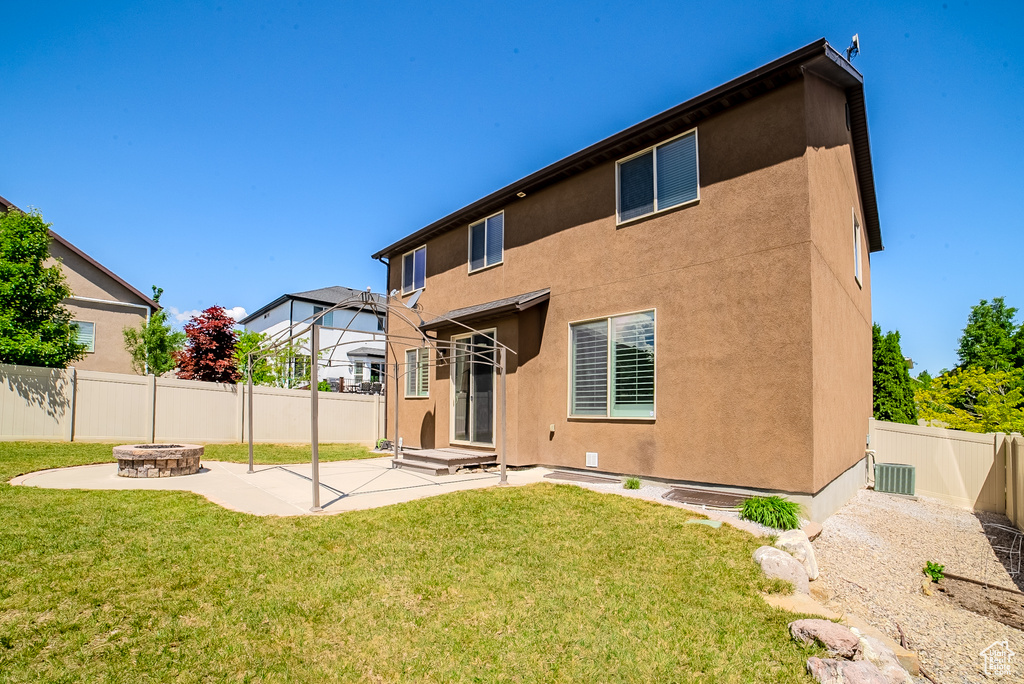 Rear view of house featuring a fire pit, a patio, stucco siding, and central AC