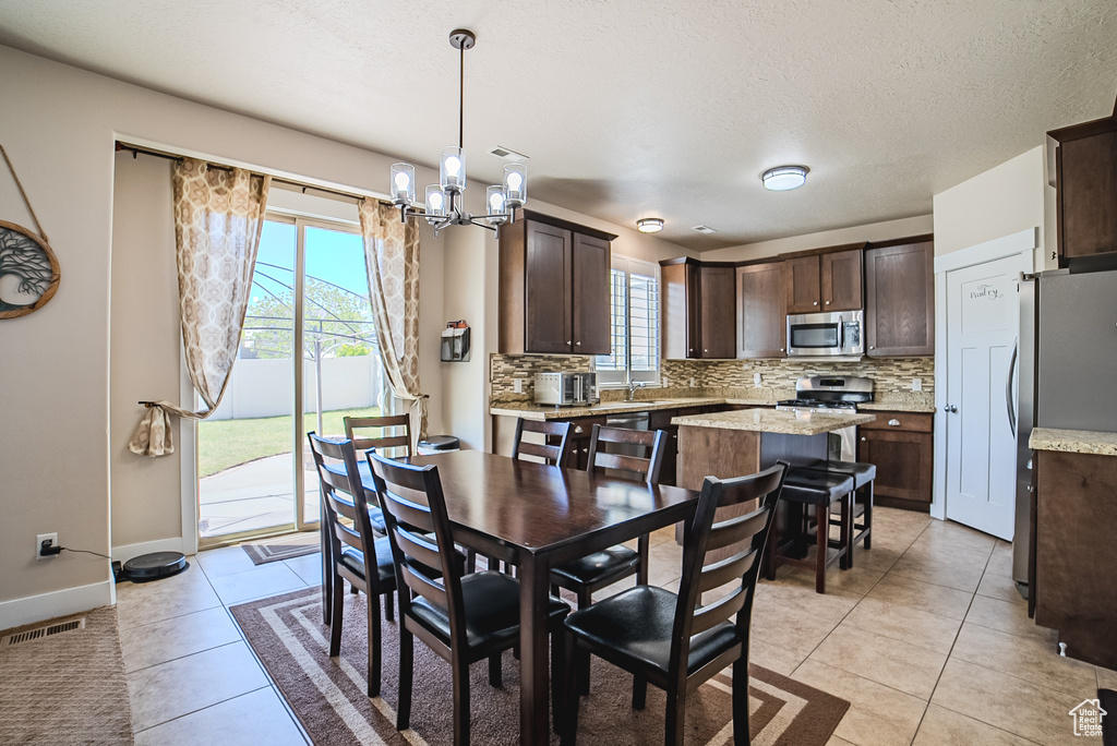 Dining space with a chandelier, light tile patterned flooring, baseboards, and a textured ceiling