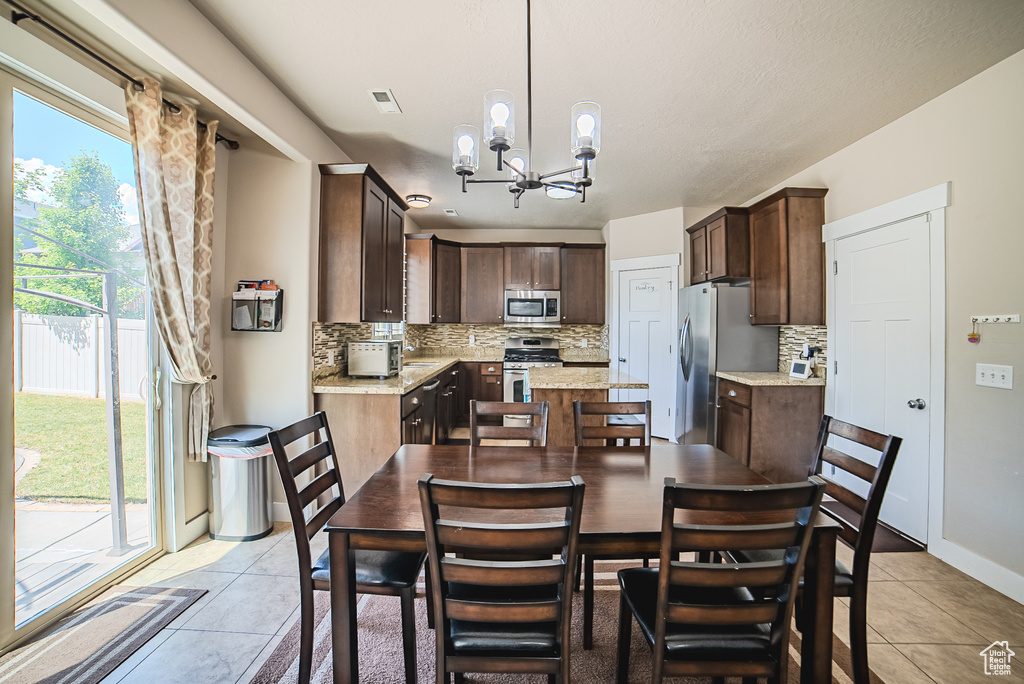 Dining space featuring light tile patterned floors, healthy amount of natural light, a chandelier, and baseboards