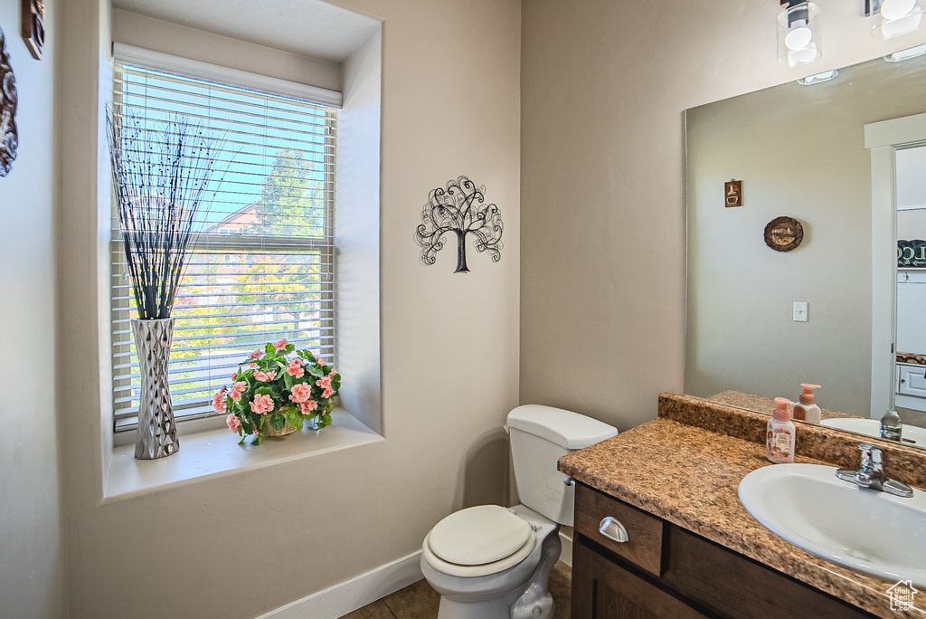 Half bath featuring vanity, toilet, and baseboards