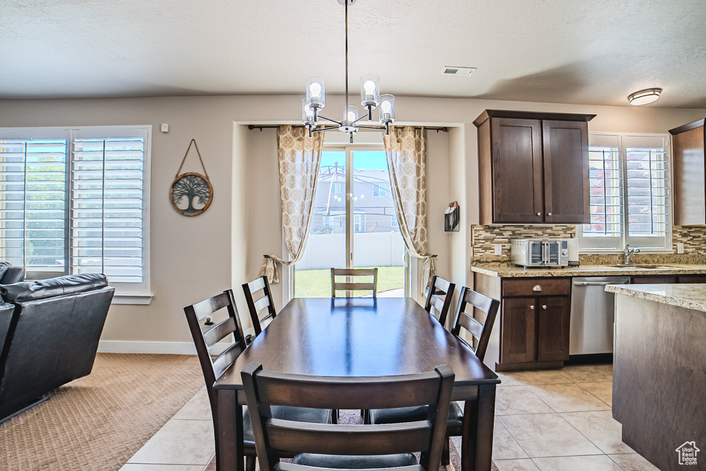 Dining space featuring a chandelier, light tile patterned floors, and healthy amount of natural light