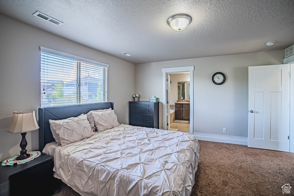 Carpeted bedroom featuring a textured ceiling, baseboards, and connected bathroom