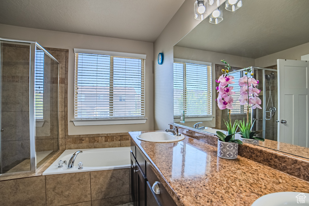Full bath with double vanity, a stall shower, and a bath