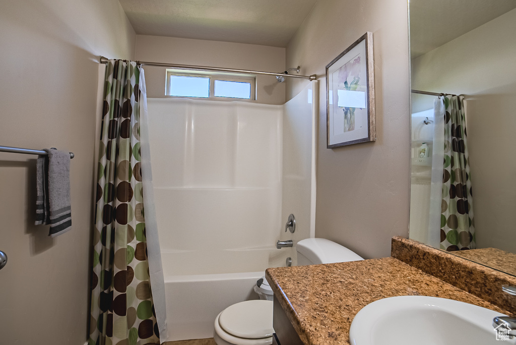 Bathroom featuring toilet, vanity, and shower / bath combo with shower curtain