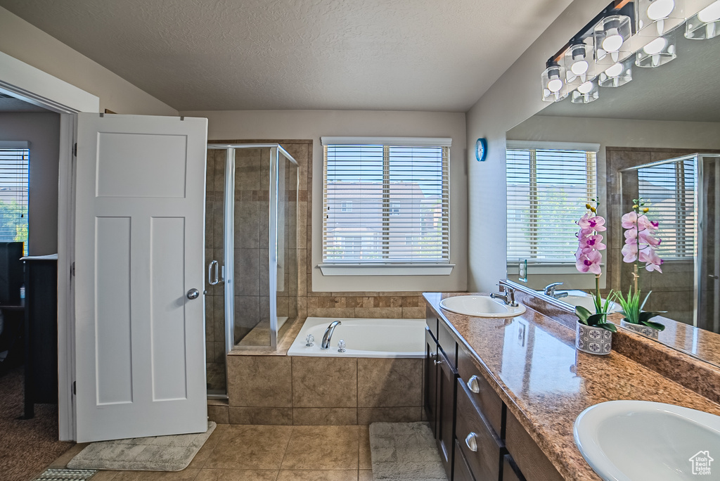 Bathroom with a shower stall, healthy amount of natural light, double vanity, and a textured ceiling