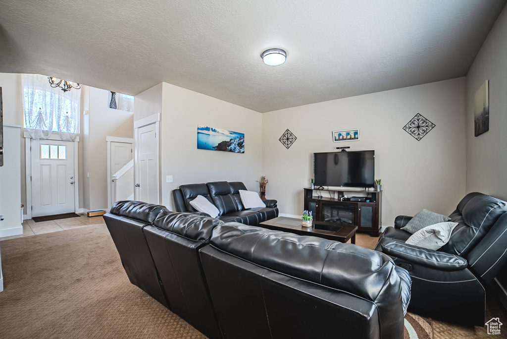 Living area featuring a chandelier, light colored carpet, light tile patterned floors, and baseboards