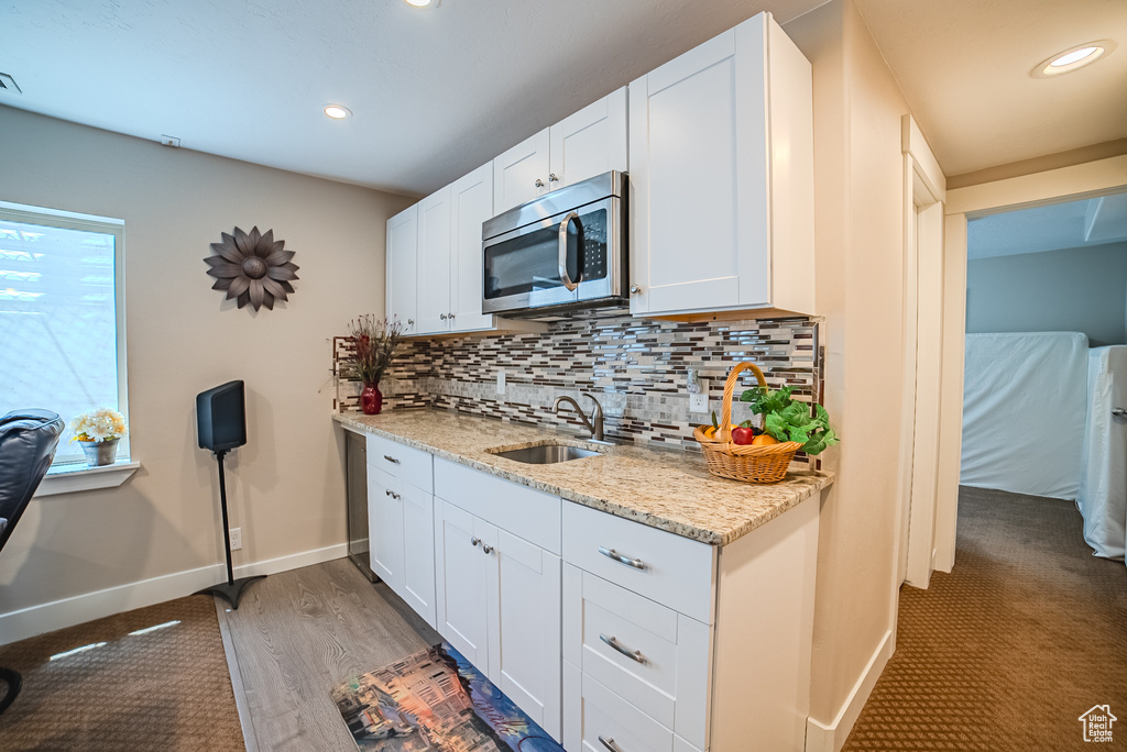 Kitchen featuring stainless steel microwave, a sink, baseboards, tasteful backsplash, and white cabinets