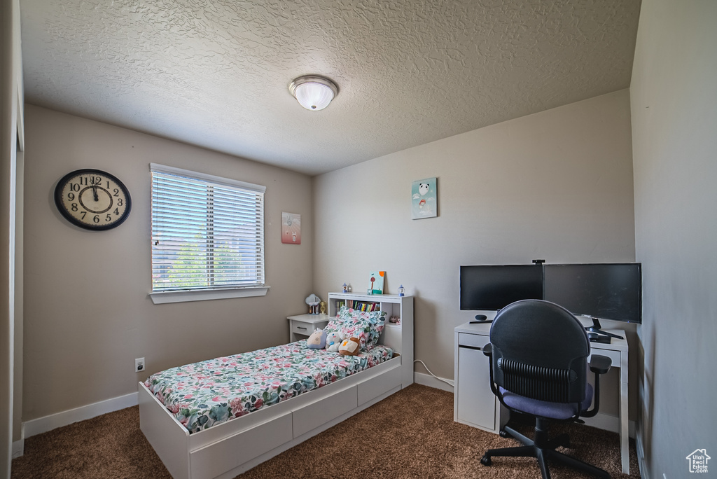 Bedroom with dark carpet, a textured ceiling, an office area, and baseboards