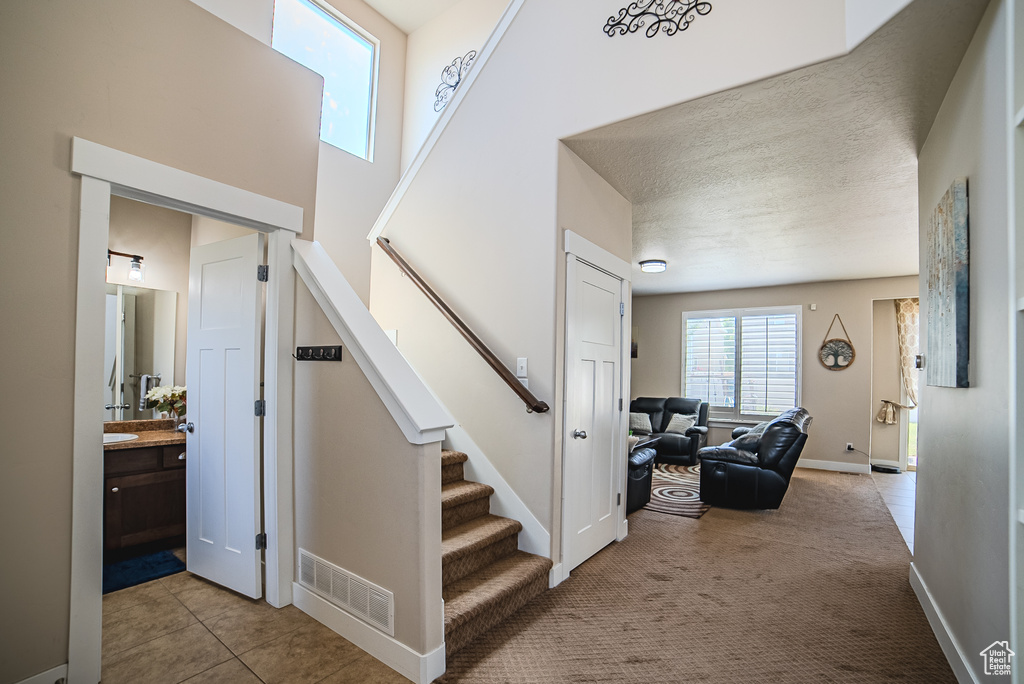 Stairs featuring tile patterned flooring, baseboards, and carpet floors