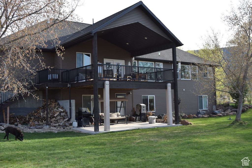 Back of property with a patio, a deck, and a lawn