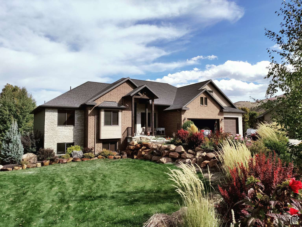 View of front of home with a garage, a front yard, and brick siding
