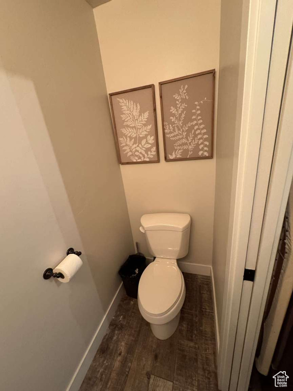 Bathroom with toilet, baseboards, and wood finished floors
