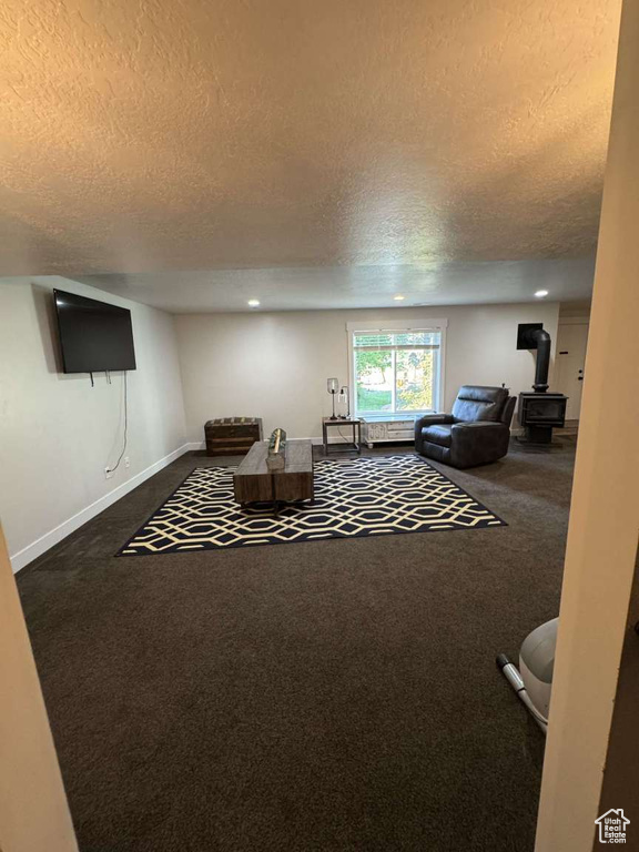 Carpeted living area with a textured ceiling, a wood stove, baseboards, and recessed lighting