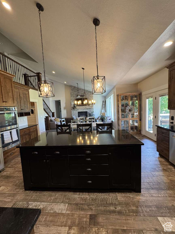 Kitchen with stainless steel appliances, dark countertops, a large island, recessed lighting, and a textured ceiling