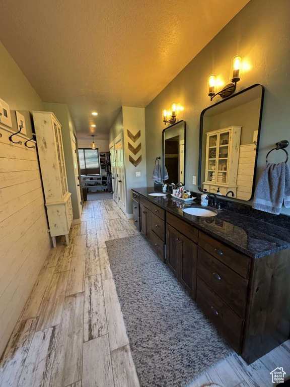 Bathroom featuring wood finished floors, double vanity, and a textured ceiling