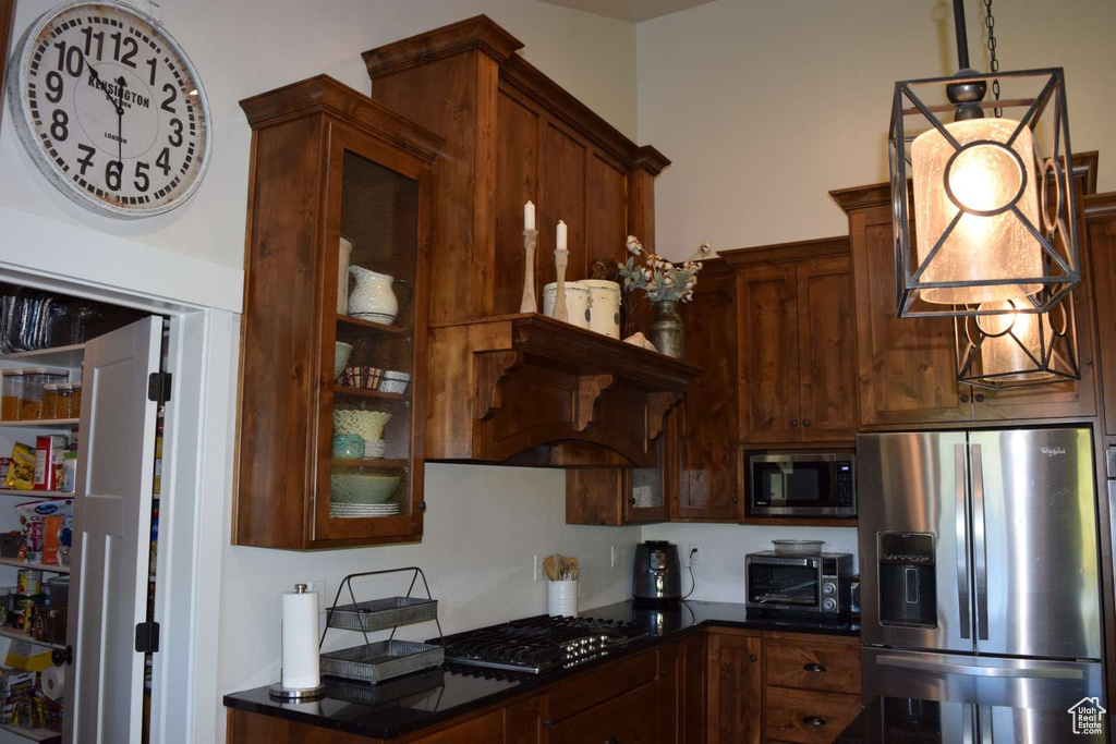 Kitchen with stainless steel appliances, glass insert cabinets, and hanging light fixtures