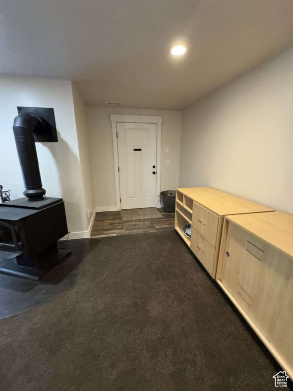 Entryway featuring a wood stove, dark colored carpet, recessed lighting, and baseboards