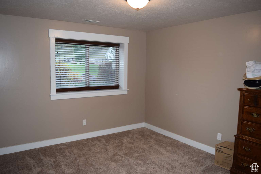 Unfurnished room with carpet floors, a textured ceiling, and baseboards