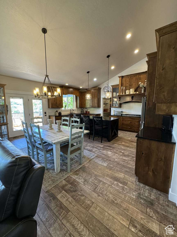 Dining area featuring a chandelier, dark wood finished floors, vaulted ceiling, and recessed lighting