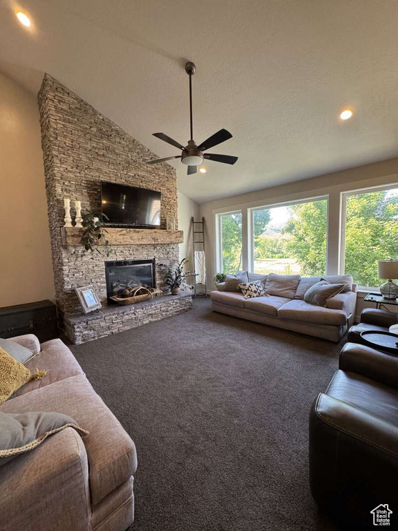 Carpeted living room with a stone fireplace, healthy amount of natural light, a ceiling fan, high vaulted ceiling, and recessed lighting