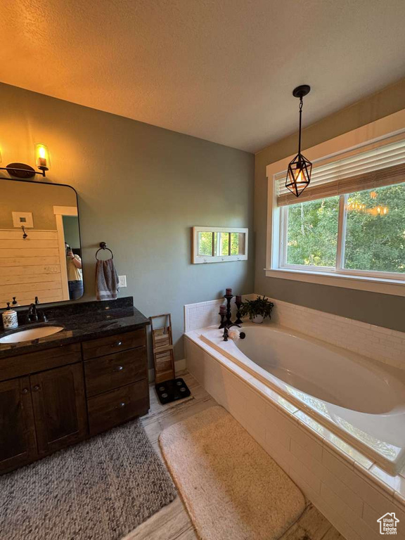 Full bath with vanity, a garden tub, and baseboards