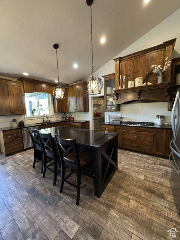 Kitchen featuring stainless steel appliances, dark countertops, recessed lighting, lofted ceiling, and a textured ceiling