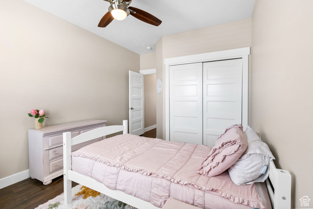 Bedroom featuring dark wood-style floors, a closet, baseboards, ceiling fan, and vaulted ceiling