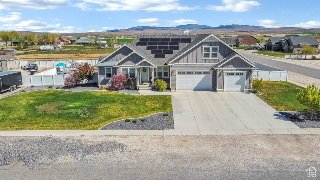 Craftsman-style home with board and batten siding, roof mounted solar panels, concrete driveway, a mountain view, and a garage